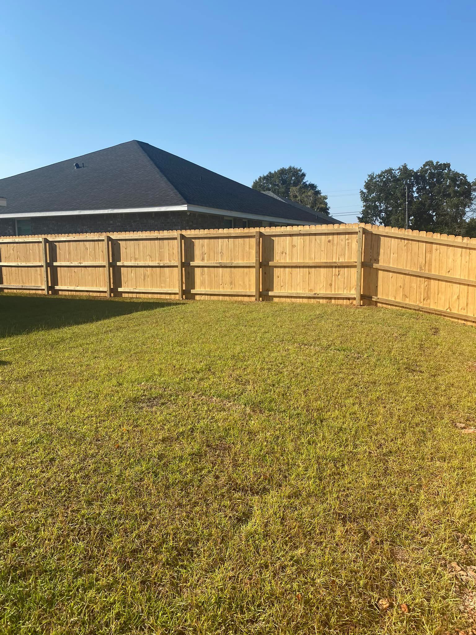 Wood privacy fence around a yard shown by Pensacola Precision Fencing
